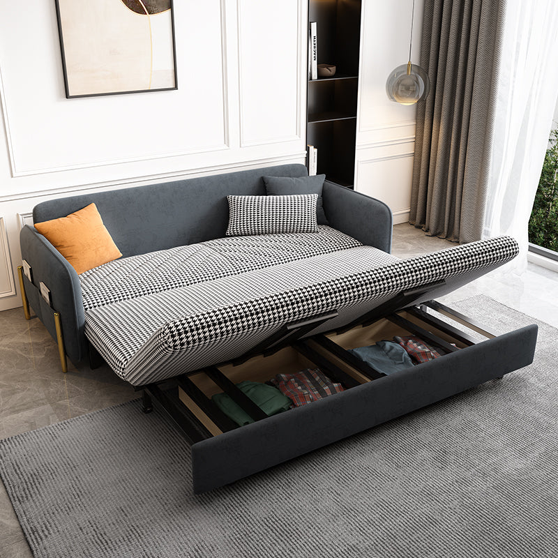 Gray velvet sofa bed with pull-out mechanism in a room with curtains and a rug.