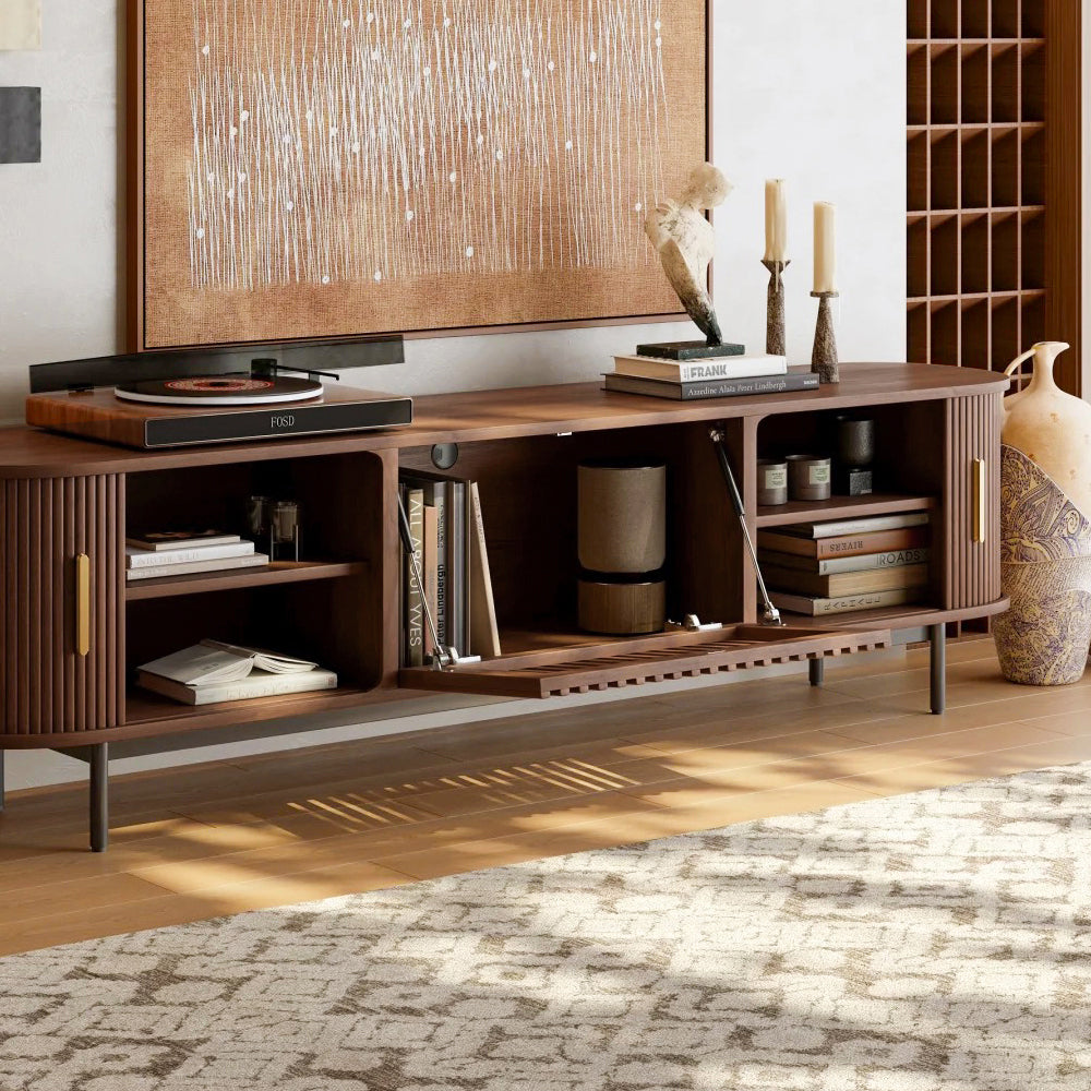 Walnut tv stand with sliding side doors and flip-down center door opening in a room with a rug and wall art.