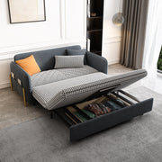 Gray velvet sleeper sofa with pull-out drawer in a guest room with curtains and a rug.